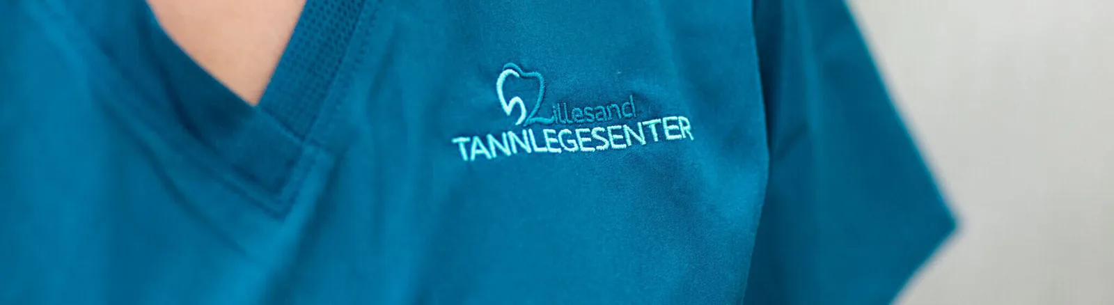 Logoen til Lillesand Tannlegesenter på arbeidstøyet til en av medarbeiderne